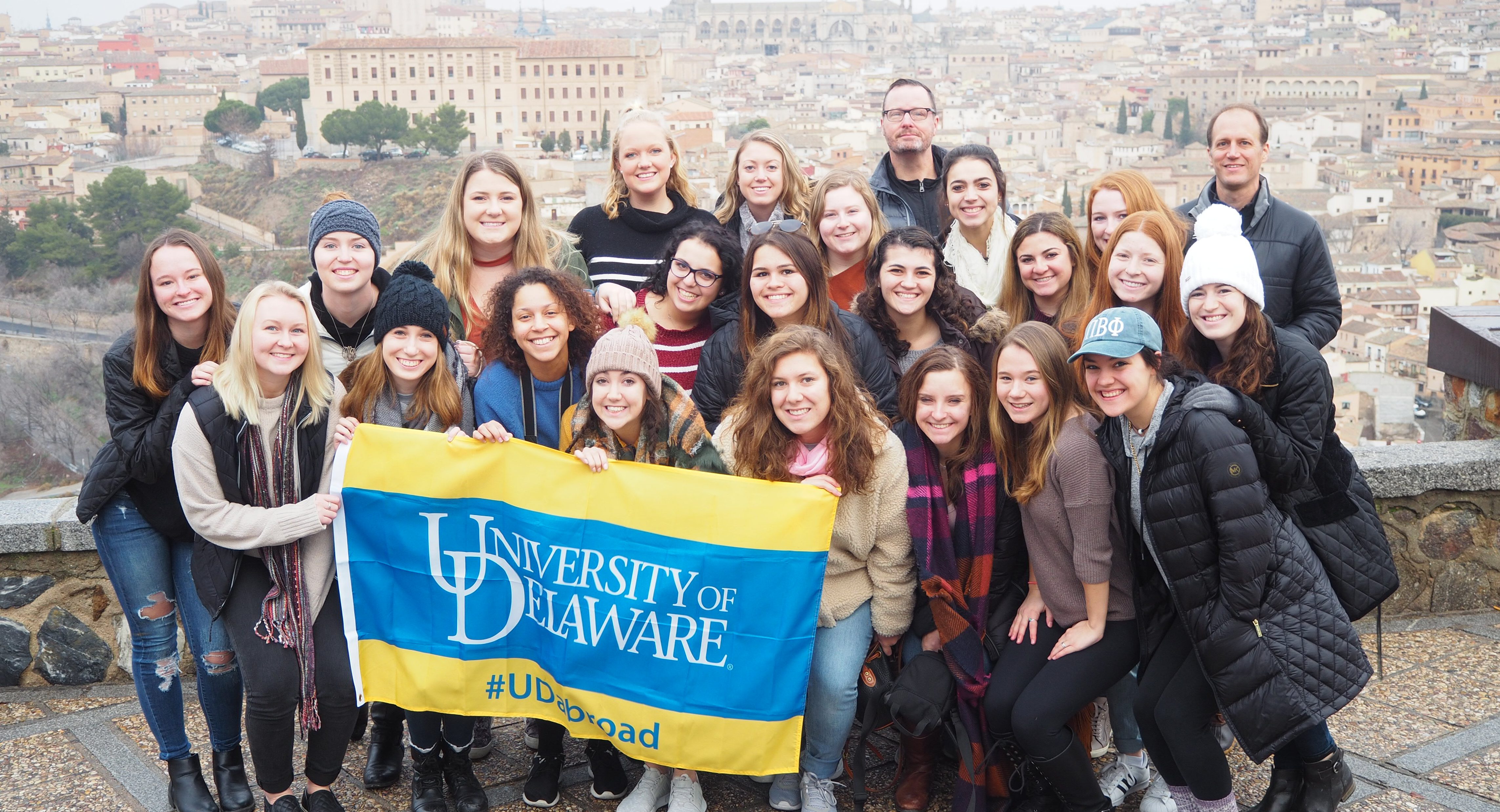 Students hold UD banner in Spain while studying abroad