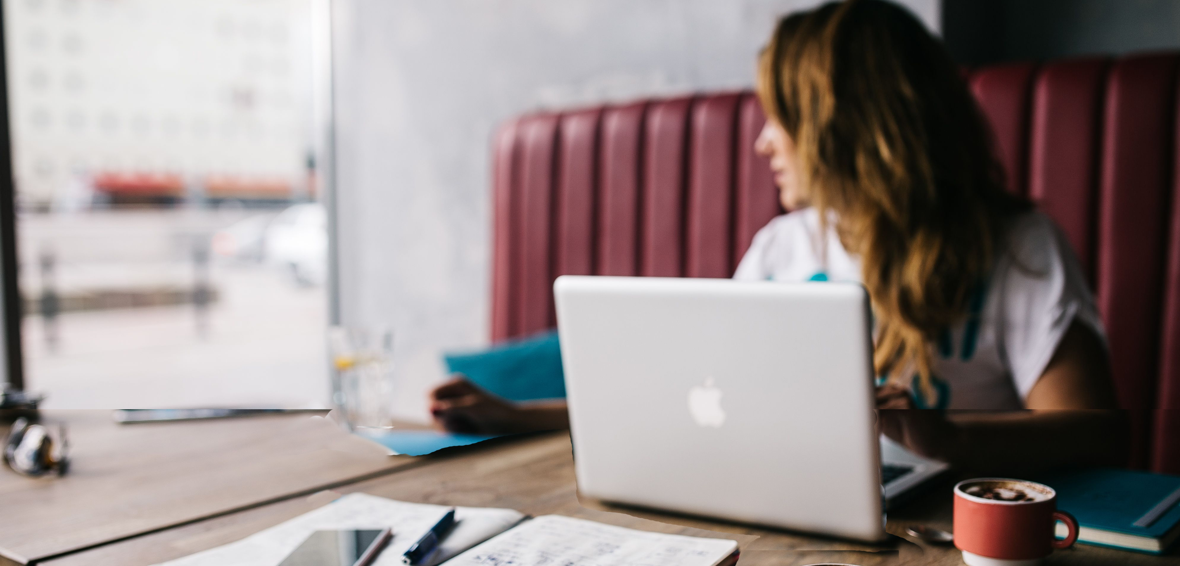 Woman looks out window sadly while working on laptop