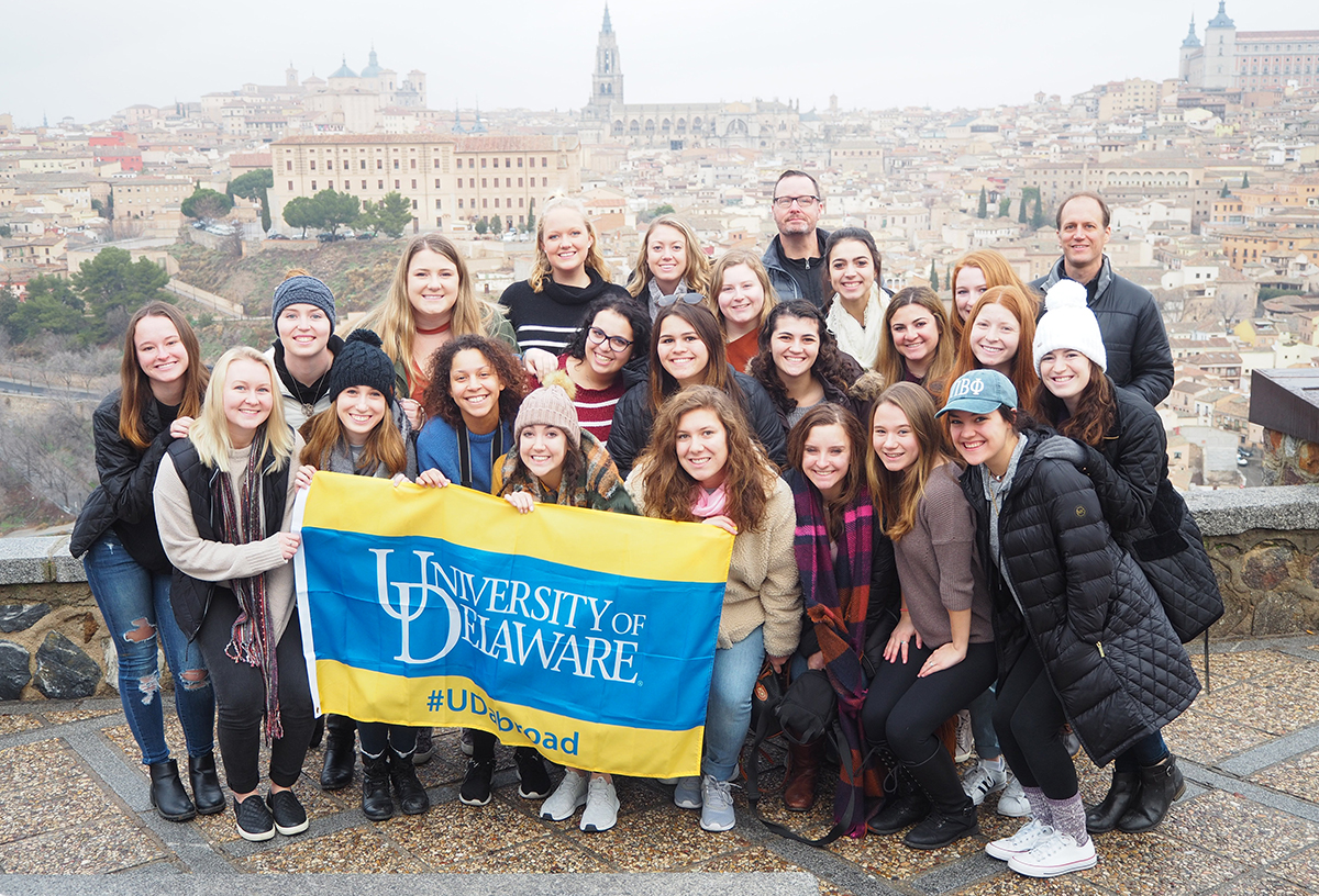 Students hold UD banner in Spain while studying abroad