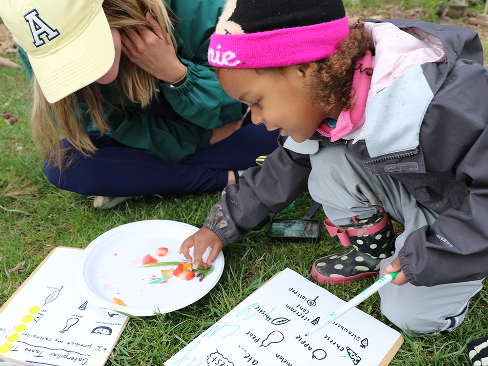 Girl uses examines caterpillar through magnifying glass