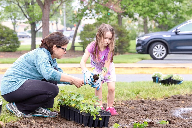 Adult and child add plants to garden on the Children's Campus