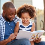 A father reads to his daughter.