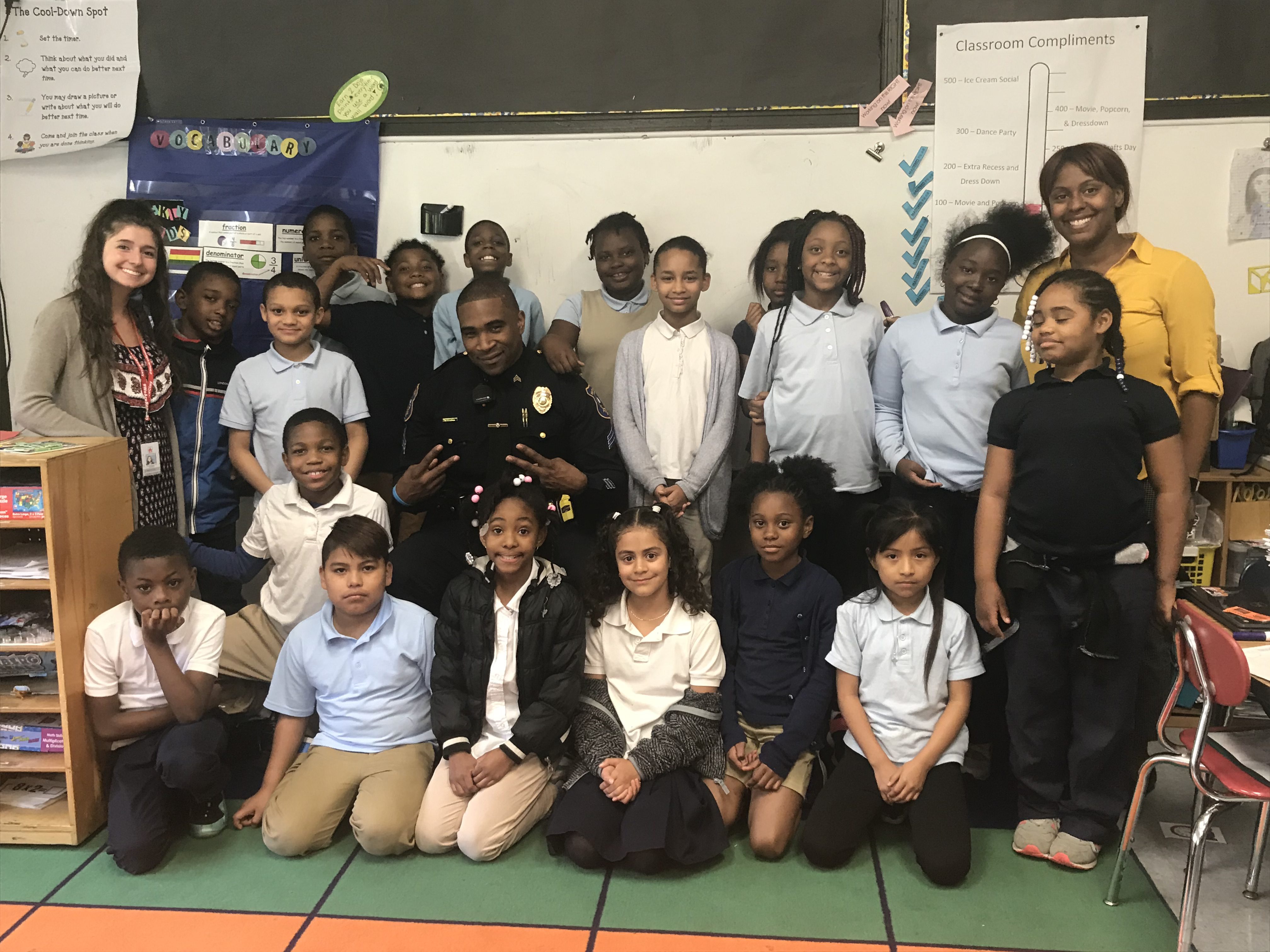 An elementary class at Warner Elementary poses for a group photo with a community police officer.