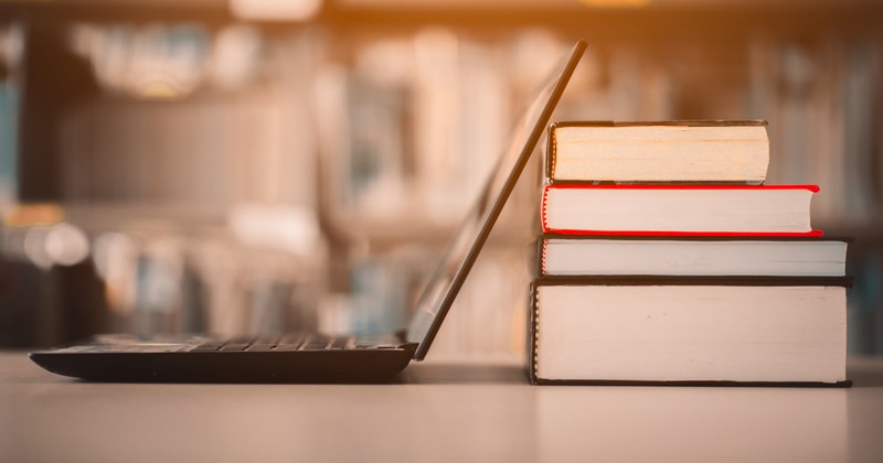 Laptop resting against a stack of books