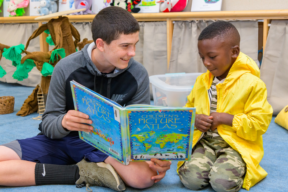 Undergraduate student reading to child at The College School