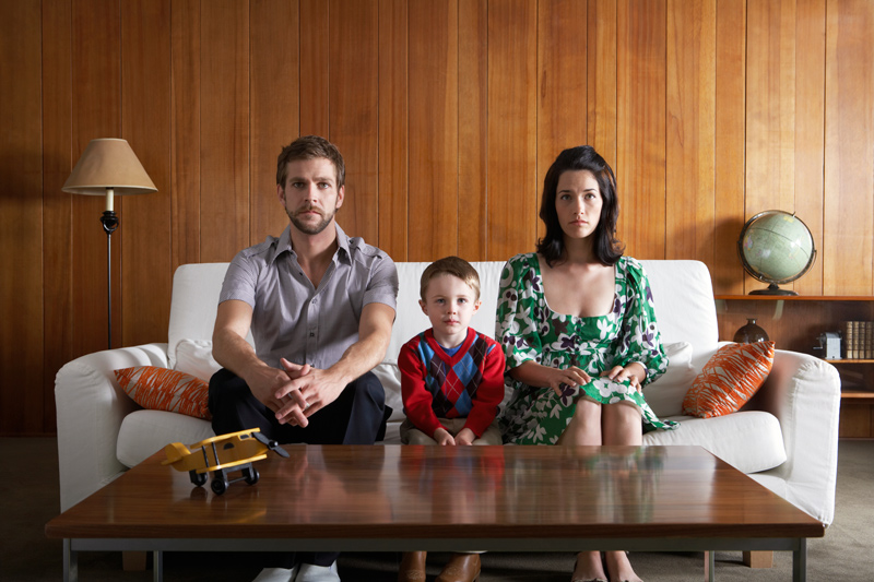 Father, mother and child sitting on couch