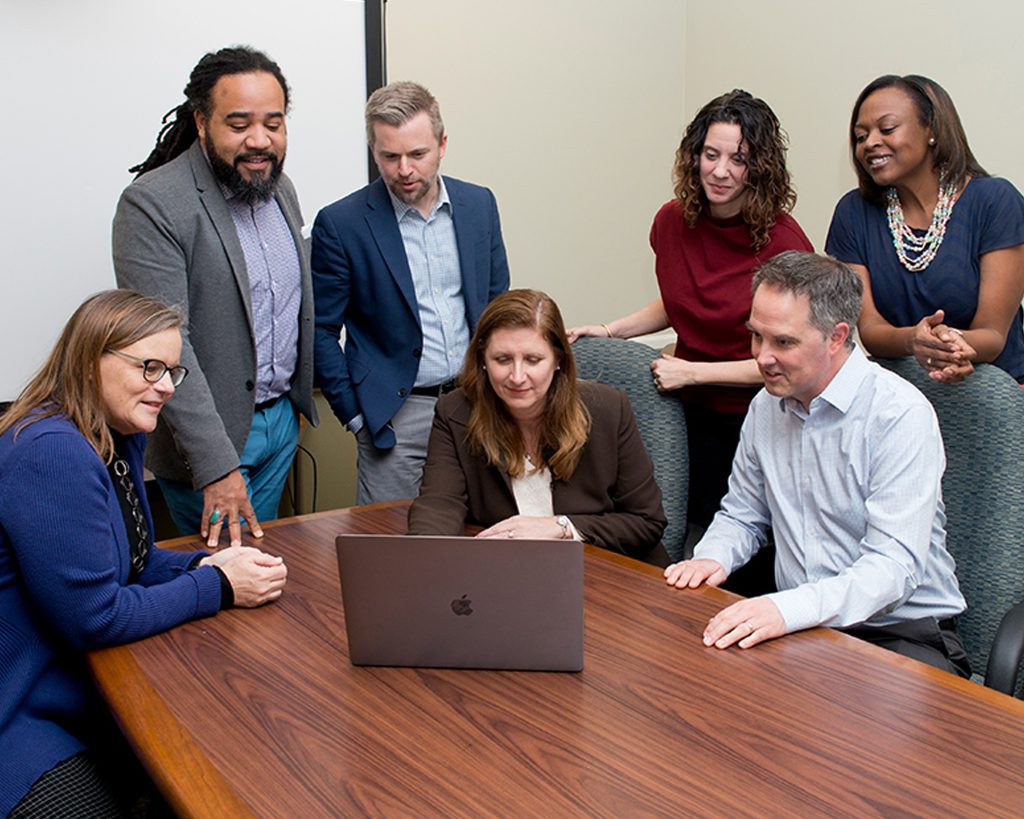 Faculty members gathered around a laptop