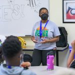 Person leading discussion among students at tables.