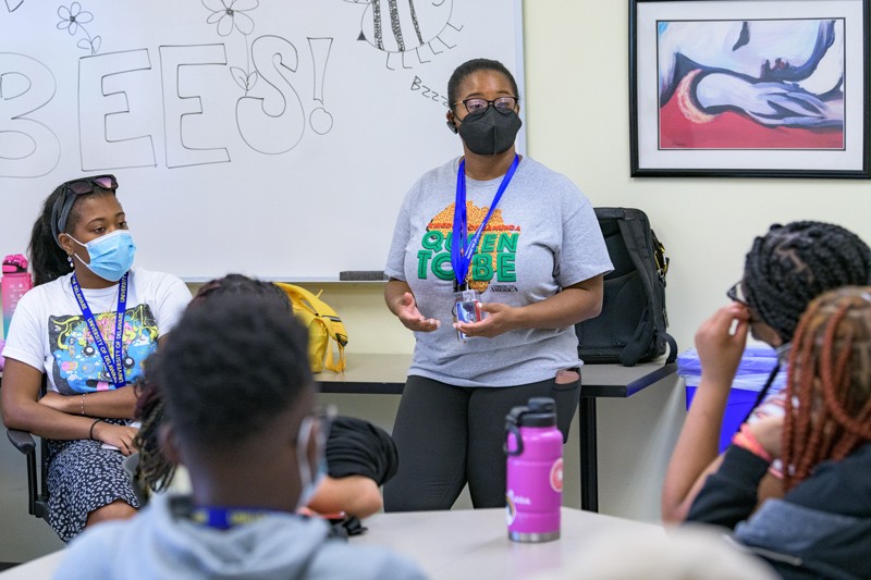 Person leading discussion among students at tables.