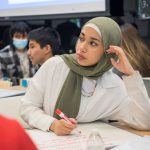 Female student sitting at desk writing on paper