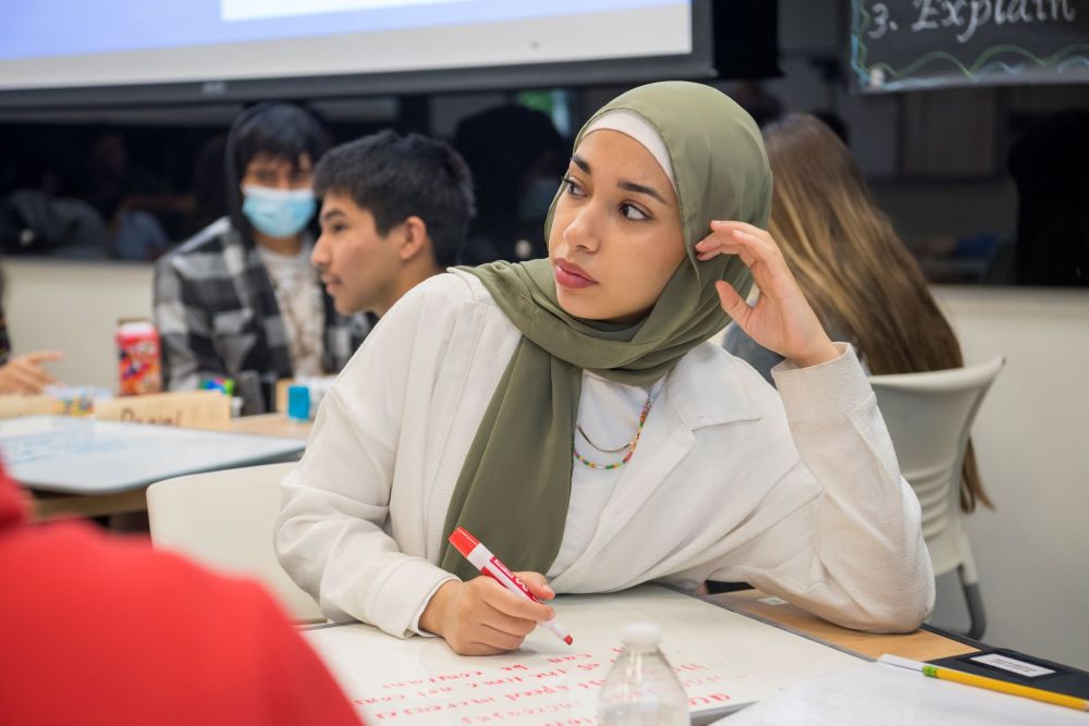 Female student sitting at desk writing on paper