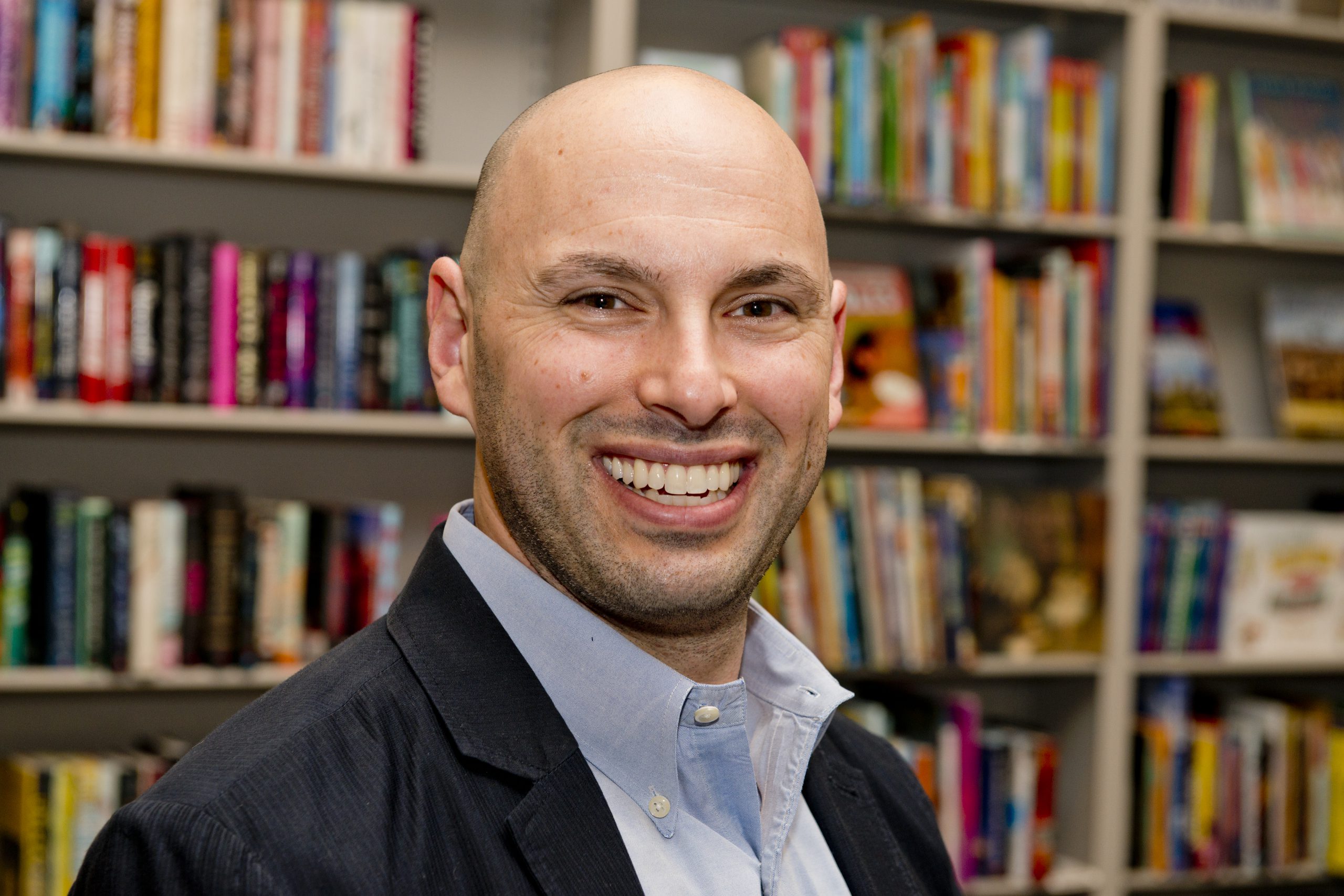 headshot of Joshua Wilson with books in the background