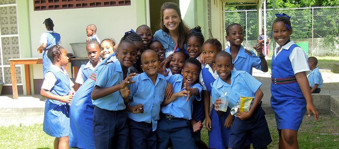 CEHD student with a group of children in school uniforms while studying abroad in barbados