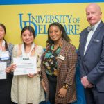 Two female high school students with their educators rising certificates, standing next to Deandra Taylor and Dean Gary Henry