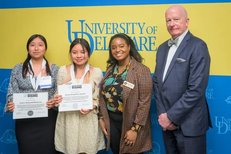 Two female high school students with their educators rising certificates, standing next to Deandra Taylor and Dean Gary Henry