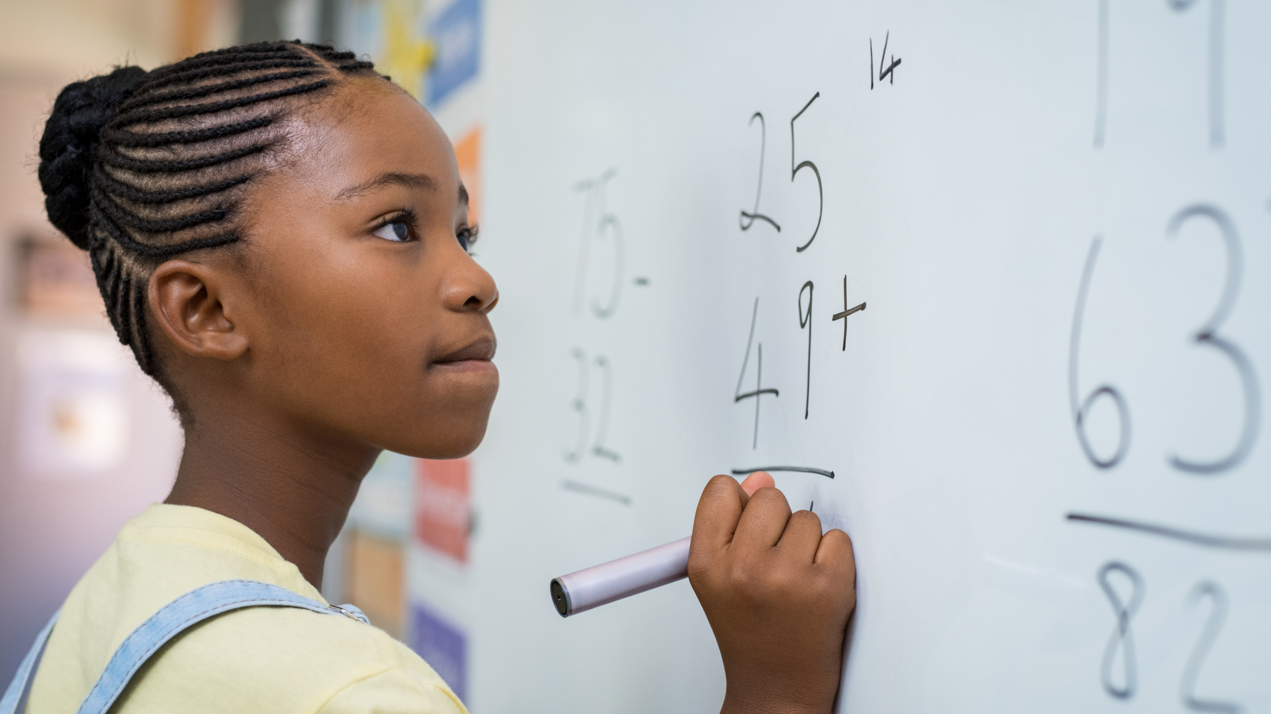 Young girl solving a math problem on a whiteboard