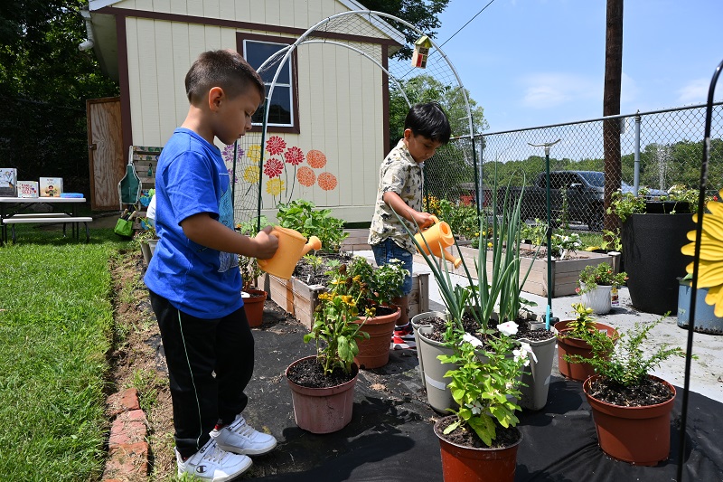 Children at Pirulo’s Child Care and Learning Center water flowers and other plants in their garden.