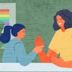 An adolescent student works with a teacher individually at a table with a rainbow flag behind them.