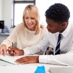 Female career services professional works with a male undergraduate student at a table.