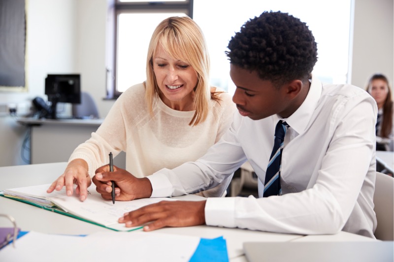 Female career services professional works with a male undergraduate student at a table.